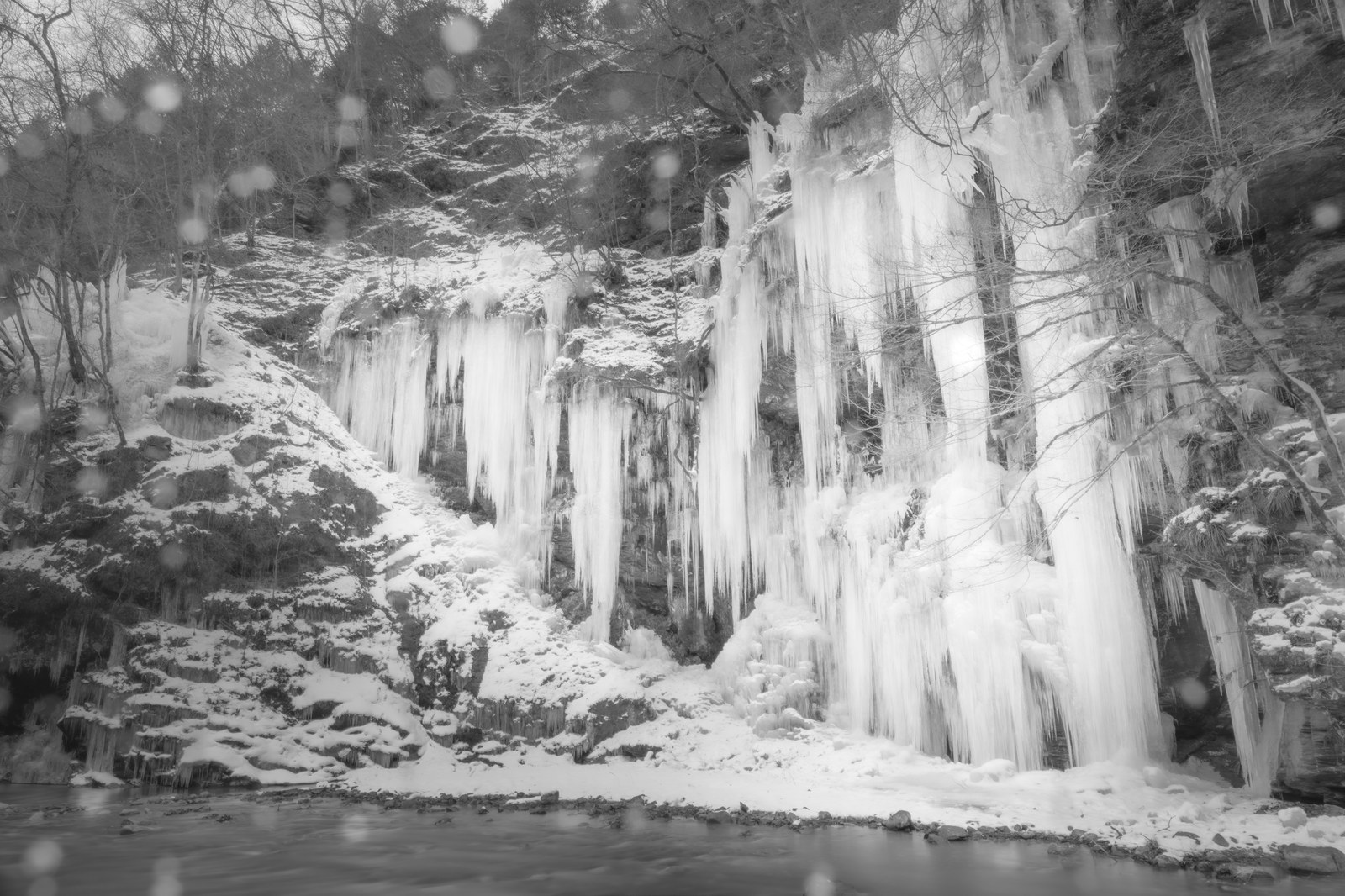 Natural icicles glowing blue on a rock wall beside the Arakawa river in Okuchichibu