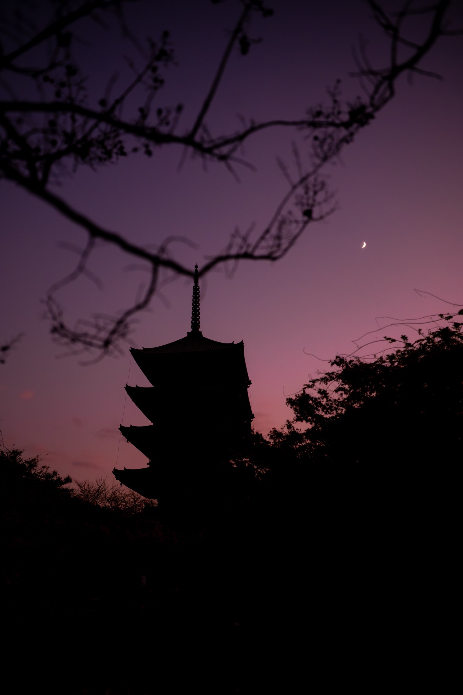 Silhouette of Toji's five-storey pagoda standing against a dusk sky with a crescent moon above it