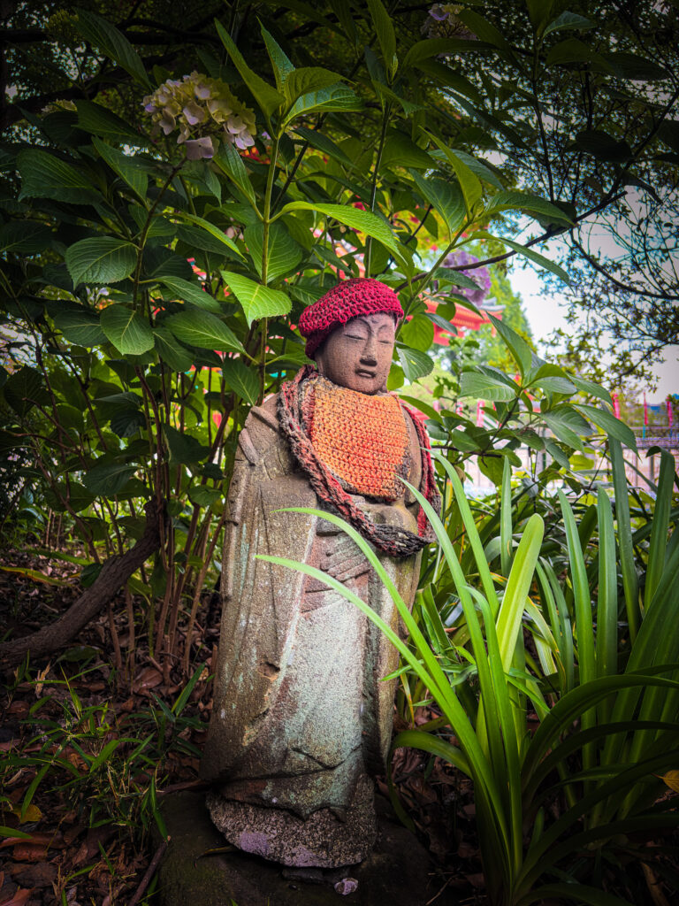Jizo statue with knitted hat and hydrangeas