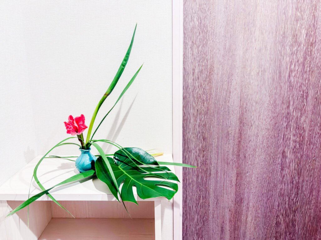 玄関に飾ったグラジオラスとモンステラの一輪挿しいけばな作品。Entryway ikebana arrangement with gladiolus and monstera in a single-flower vase.