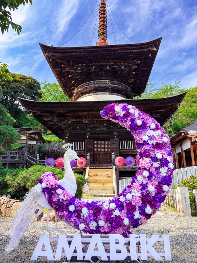 花で装飾された白い孔雀のオブジェと三重塔
White peacock statue made of flowers in front of a pagoda
