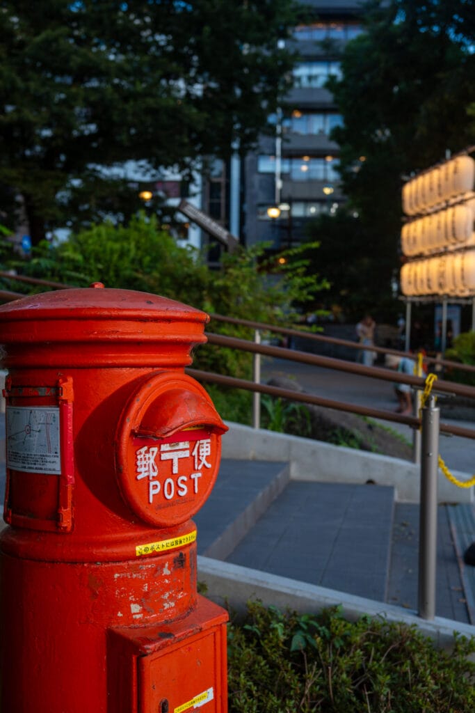 Red postbox and glowing lanterns at dusk in Ueno Park

